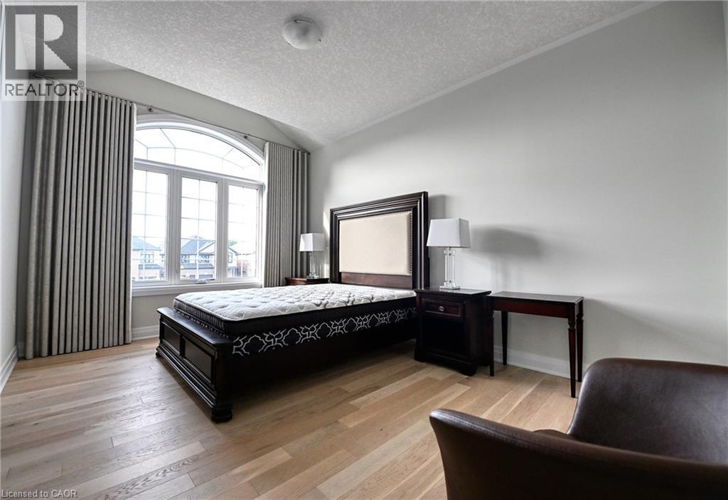 Arched window with extensive glazing, light wood-finish flooring, and neutral wall tones - 923 Eaglecrest Court, Kitchener, ON - Indoor Photo Showing Bedroom