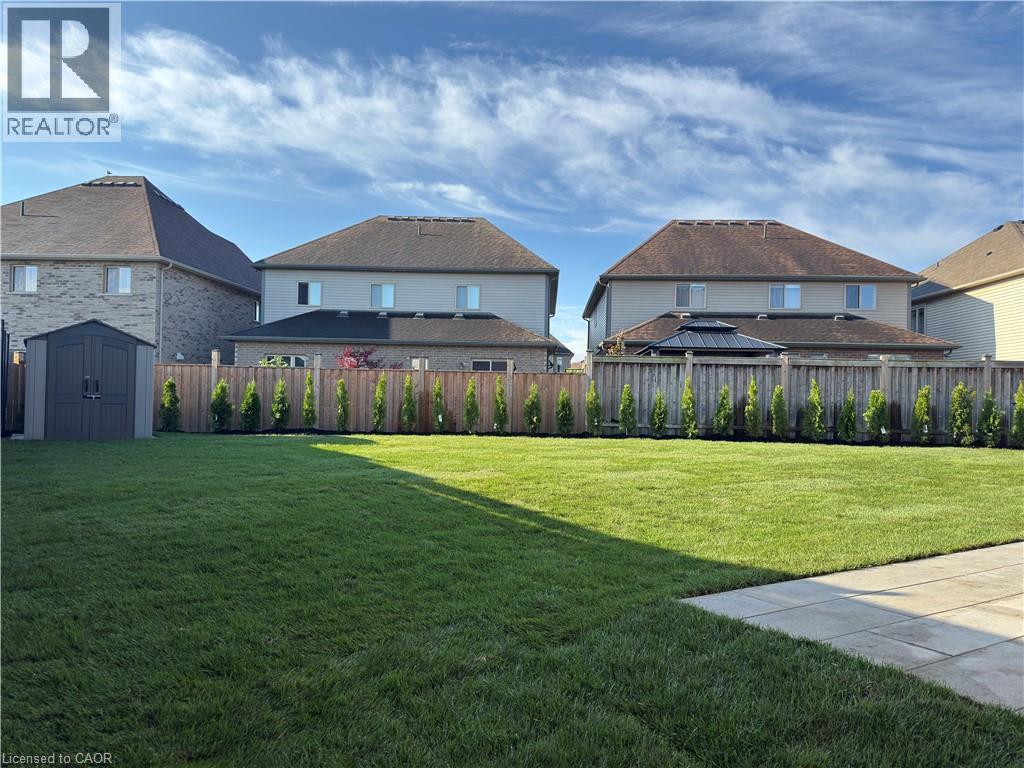 Expansive green lawn, paver patio, wood privacy fence, and manicured evergreen plantings - 923 Eaglecrest Court, Kitchener, ON - Outdoor With Deck Patio Veranda