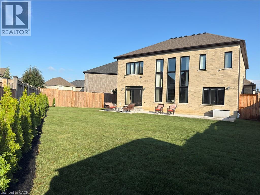 Expansive backyard featuring a manicured lawn, a full wooden fence, and a row of evergreen trees - 923 Eaglecrest Court, Kitchener, ON - Outdoor