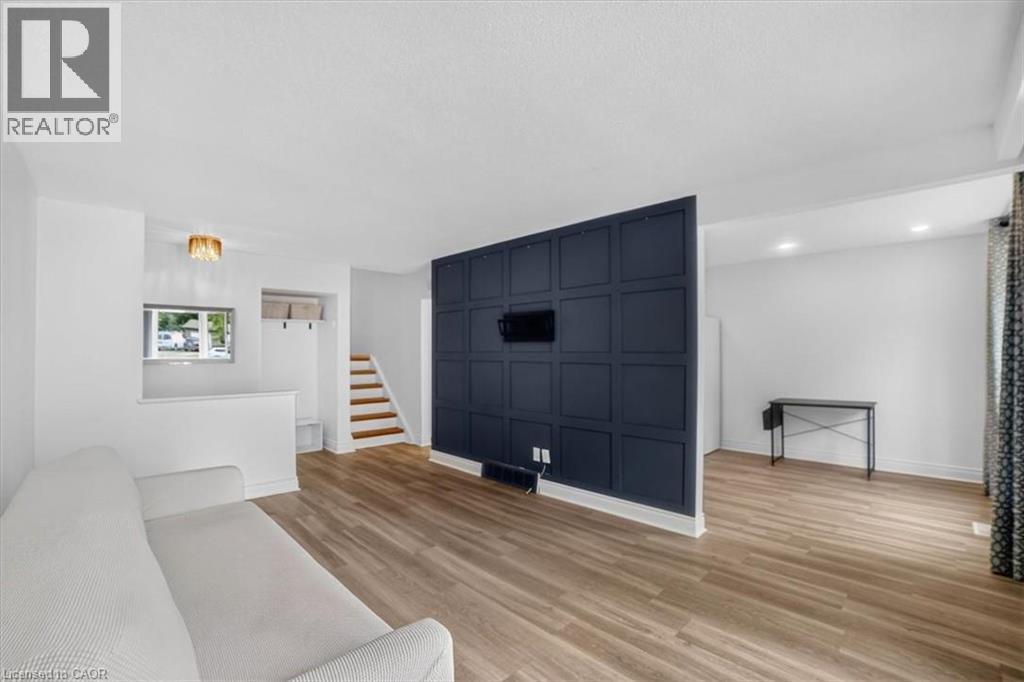 Wood-finish flooring throughout, a decorative accent wall, recessed lighting, and a built-in stairwell coat rack - 27 Gretna Court, Hamilton, ON - Indoor