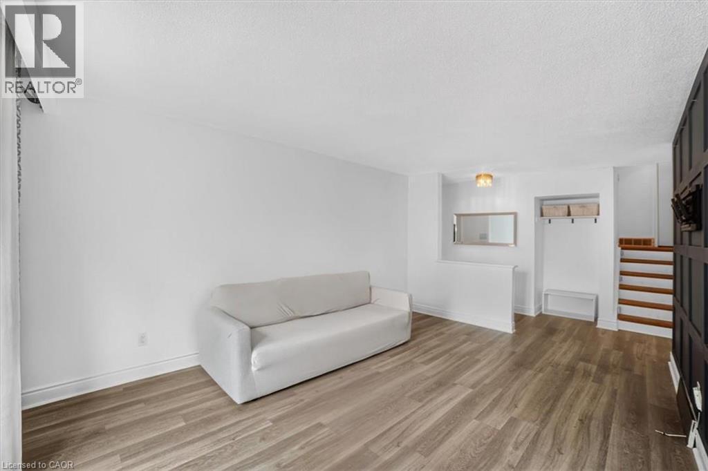 Wood-finish flooring, white wall finishes, built-in storage niche, wood stair treads, and a semi-flush mount ceiling light - 27 Gretna Court, Hamilton, ON - Indoor Photo Showing Other Room