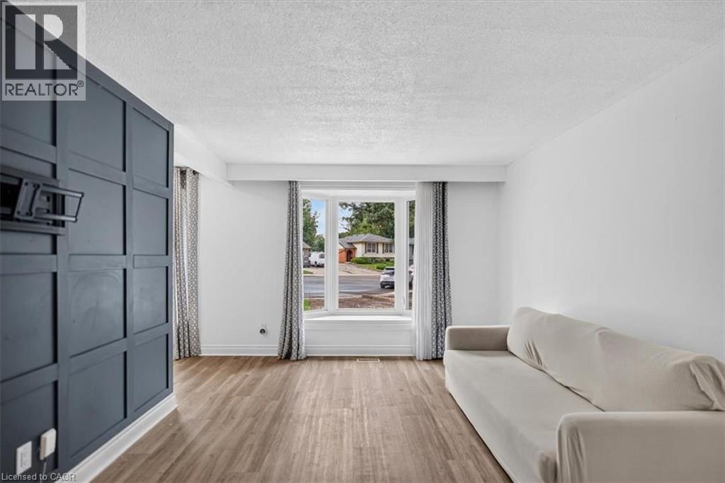 Wood-finish flooring throughout, bright white walls, and a large bay window - 27 Gretna Court, Hamilton, ON - Indoor