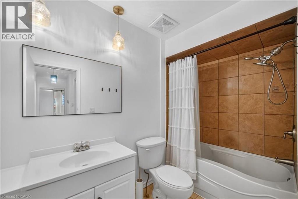 Bathroom featuring a vanity with an integrated sink, a rectangular mirror, a shower-tub combination, and tiled shower surround - 27 Gretna Court, Hamilton, ON - Indoor Photo Showing Bathroom