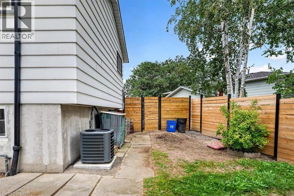 Exterior featuring horizontal siding, a concrete foundation, a ground-mounted HVAC unit, a wood privacy fence, and mature trees - 27 Gretna Court, Hamilton, ON - Outdoor