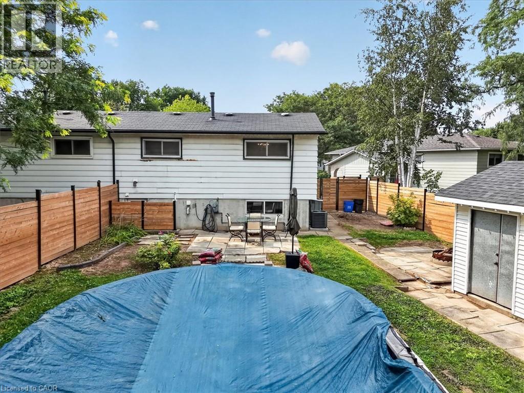 Backyard with a swimming pool, stone patio, wooden fencing, and a separate storage shed - 27 Gretna Court, Hamilton, ON - Outdoor