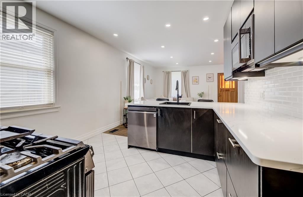 Gourmet kitchen featuring a stainless steel dishwasher, white subway tile backsplash, recessed lighting, and white countertops - 34 St Clair Avenue, Kitchener, ON - Indoor Photo Showing Kitchen