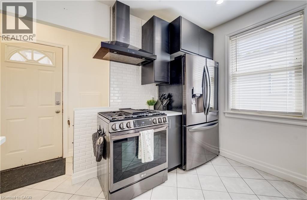 Stainless steel appliances, white subway tile backsplash, dark cabinetry, and white tile flooring - 34 St Clair Avenue, Kitchener, ON - Indoor Photo Showing Kitchen
