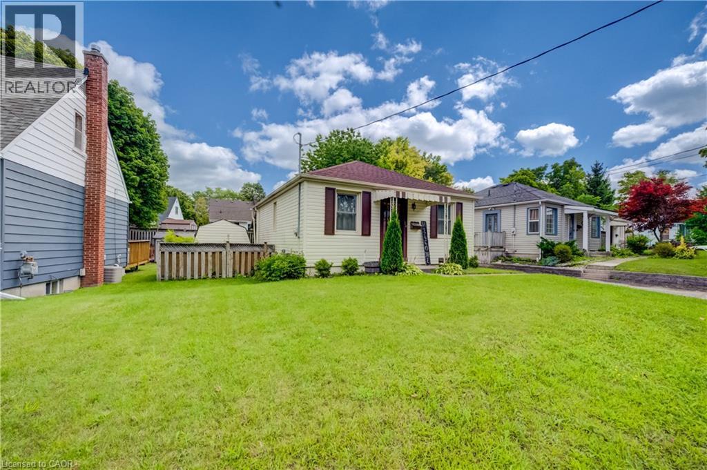 Expansive lawn with mature trees, a covered front porch, and a paved walkway - 34 St Clair Avenue, Kitchener, ON - Outdoor