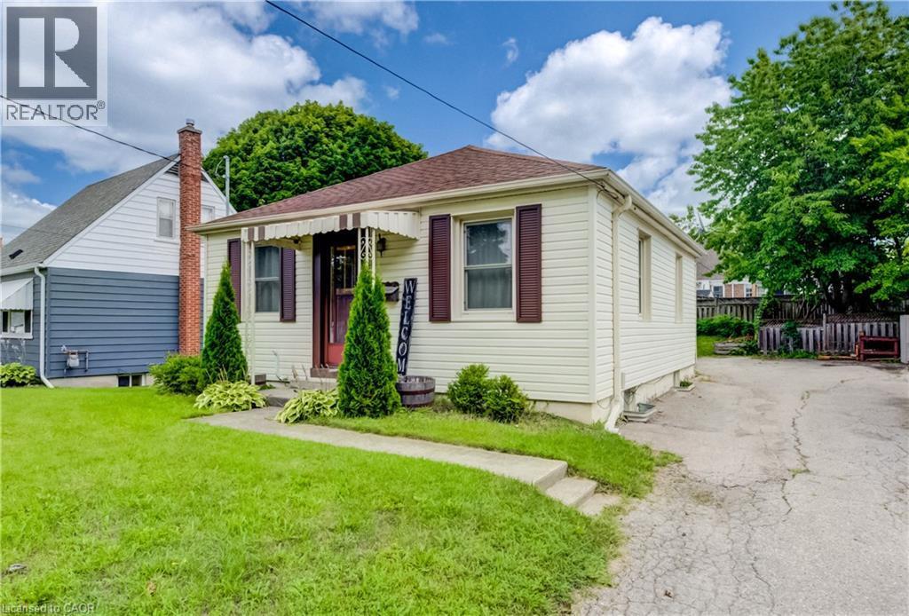 Single-story residence featuring siding exterior, a front entry awning, and a paved driveway - 34 St Clair Avenue, Kitchener, ON - Outdoor