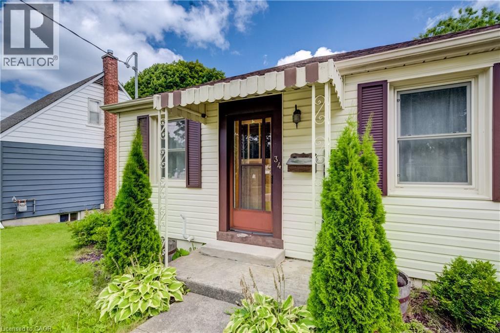 Cream-colored siding, brown window shutters, and a front entry door with decorative glass - 34 St Clair Avenue, Kitchener, ON - Outdoor With Exterior
