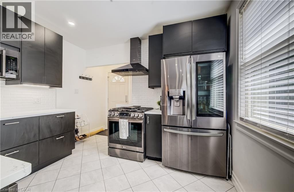 Modern kitchen featuring dark cabinetry, stainless steel appliances, white subway tile backsplash, and white countertops - 34 St Clair Avenue, Kitchener, ON - Indoor Photo Showing Kitchen
