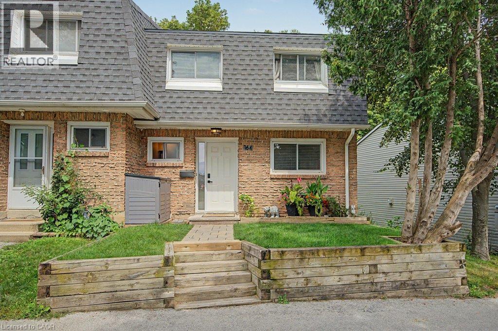 Brick facade with a white entry door, dormer windows, and a shingle roof - 2050 Upper Middle Road Unit# 164, Burlington, ON - Outdoor