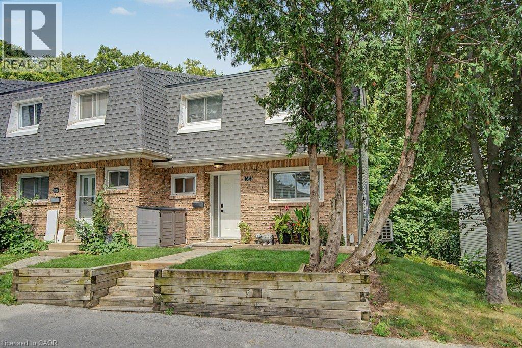 Brick exterior with dormer windows, a gray shingle roof, and a wood-tie retaining wall with steps - 2050 Upper Middle Road Unit# 164, Burlington, ON - Outdoor