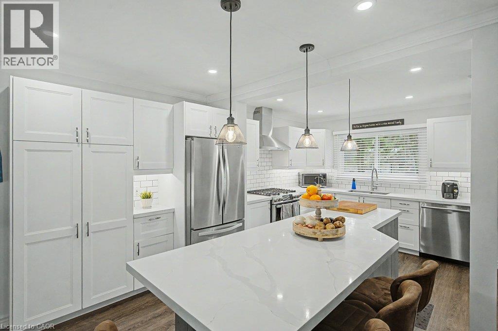 White shaker cabinetry, stainless steel appliances, white subway tile backsplash, white countertop island, and recessed lighting - 2050 Upper Middle Road Unit# 164, Burlington, ON - Indoor Photo Showing Kitchen With Upgraded Kitchen