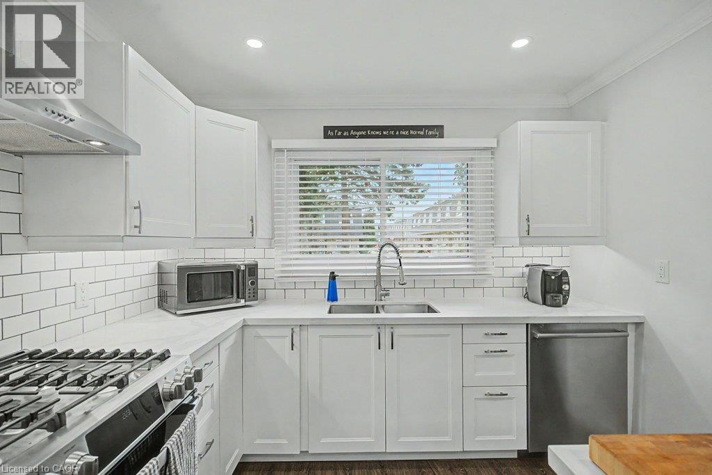 White shaker-style cabinetry, subway tile backsplash, stainless steel appliances, corner sink, and recessed lighting - 2050 Upper Middle Road Unit# 164, Burlington, ON - Indoor Photo Showing Kitchen With Double Sink With Upgraded Kitchen
