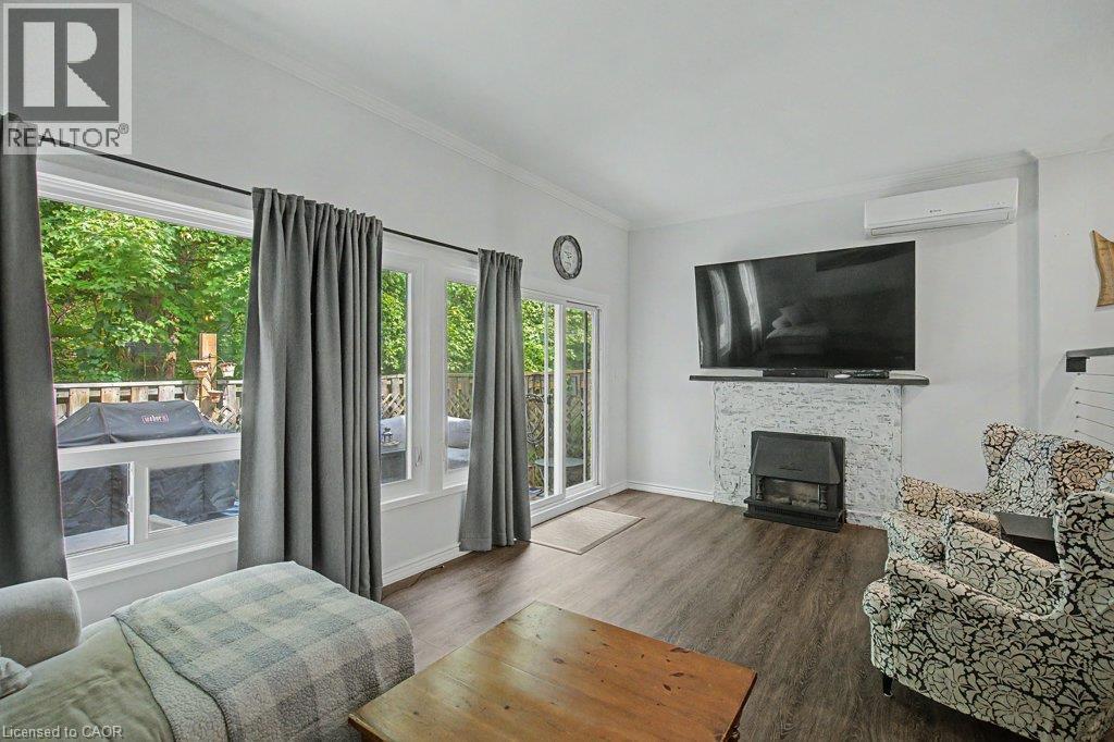Living space with wood-finish flooring, a white-painted brick fireplace, and integrated heating/cooling unit - 2050 Upper Middle Road Unit# 164, Burlington, ON - Indoor Photo Showing Living Room With Fireplace