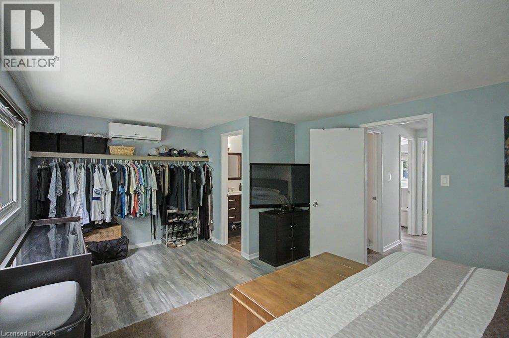 Wood-finish flooring, built-in shelving, mini-split air conditioning unit, and a window with blinds - 2050 Upper Middle Road Unit# 164, Burlington, ON - Indoor Photo Showing Bedroom