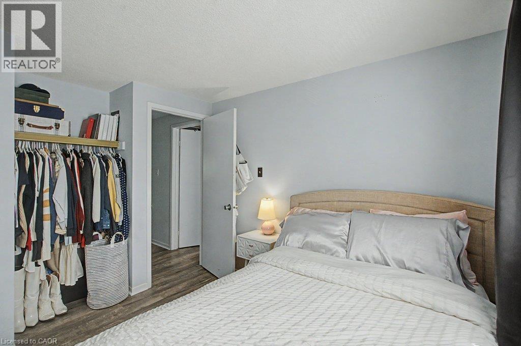 Bedroom featuring a built-in closet with shelving, wood-finish flooring, and a white interior door - 2050 Upper Middle Road Unit# 164, Burlington, ON - Indoor Photo Showing Bedroom