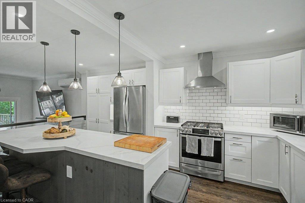 Modern kitchen featuring white cabinetry, stainless steel appliances, a subway tile backsplash, recessed lighting, and a large central island with pendant lights - 2050 Upper Middle Road Unit# 164, Burlington, ON - Indoor Photo Showing Kitchen With Upgraded Kitchen