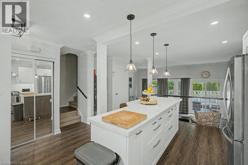 Wood-finish flooring throughout, kitchen island with built-in storage, recessed lighting, three pendant lights, and sliding glass doors - 2050 Upper Middle Road Unit# 164, Burlington, ON - Indoor Photo Showing Kitchen With Upgraded Kitchen