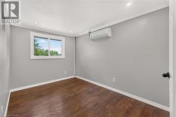 Recessed lighting, crown molding, wood-finish flooring, and a window with white trim -