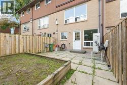 Rear exterior featuring a brick facade, white door with glass panels, large windows, and a paved patio area -