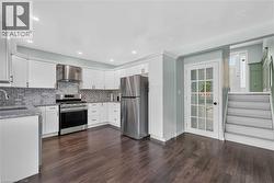 Kitchen featuring white cabinetry, stainless steel appliances, dark wood-finish flooring, and recessed lighting -
