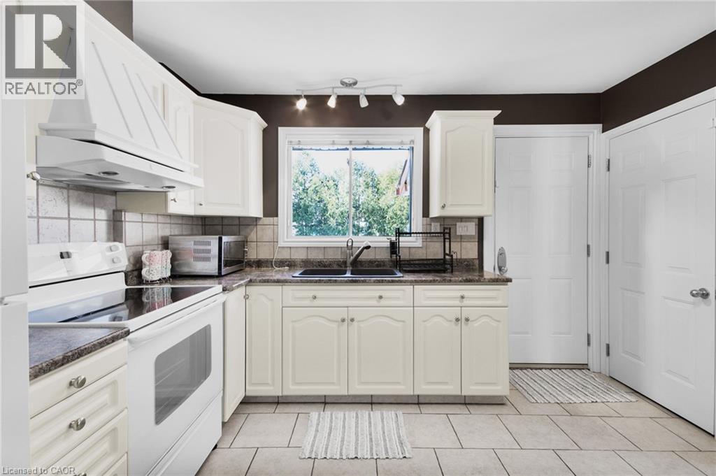 Kitchen featuring white cabinetry, gray stone-finish countertops, and a tile backsplash - 185 Burlington Street, London, ON - Indoor Photo Showing Kitchen With Double Sink