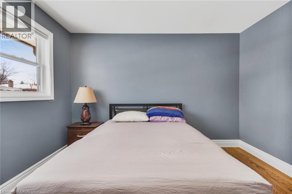 Wood-finish flooring with white baseboards, a white window frame, and neutral wall paint - 185 Burlington Street, London, ON - Indoor Photo Showing Bedroom