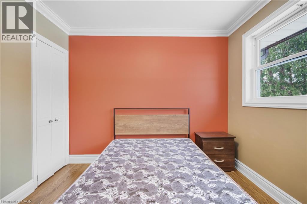 Hardwood-style flooring, white bi-fold closet doors, white window trim, and crown molding - 185 Burlington Street, London, ON - Indoor Photo Showing Bedroom