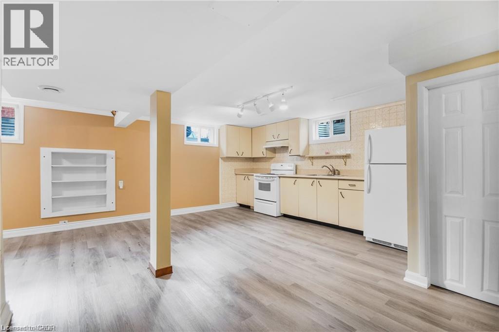 Spacious room featuring wood-finish flooring, built-in shelving, and a kitchen area with cabinetry, a sink, and appliances - 185 Burlington Street, London, ON - Indoor Photo Showing Kitchen