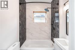 Bathtub shower combination with black accent wall tiling and white marble-patterned wall tiling - 