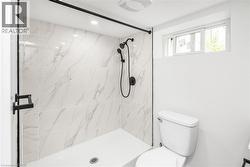 Walk-in shower with marble-look tile surround and black-finish fixtures - 