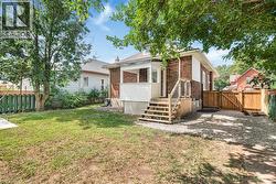 Brick exterior home with white siding accents, wood deck, gravel parking area, and wood fencing - 