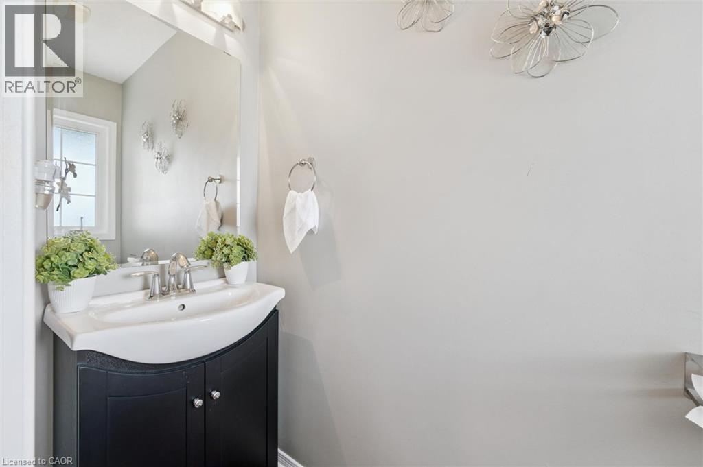 Black vanity with a white integrated sink, chrome faucet, and rectangular wall mirror - 308 Parkvale Drive, Kitchener, ON - Indoor Photo Showing Bathroom