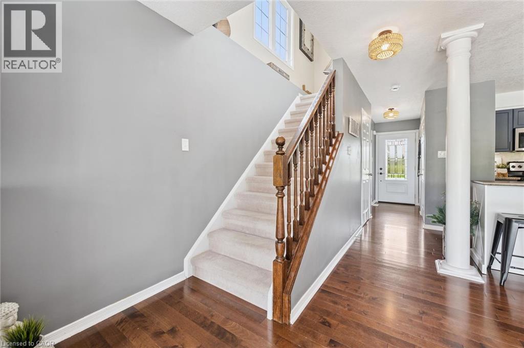 Hardwood-finish flooring, carpeted staircase with wood railing, decorative column, transom window, and built-in lighting - 308 Parkvale Drive, Kitchener, ON - Indoor Photo Showing Other Room With Fireplace