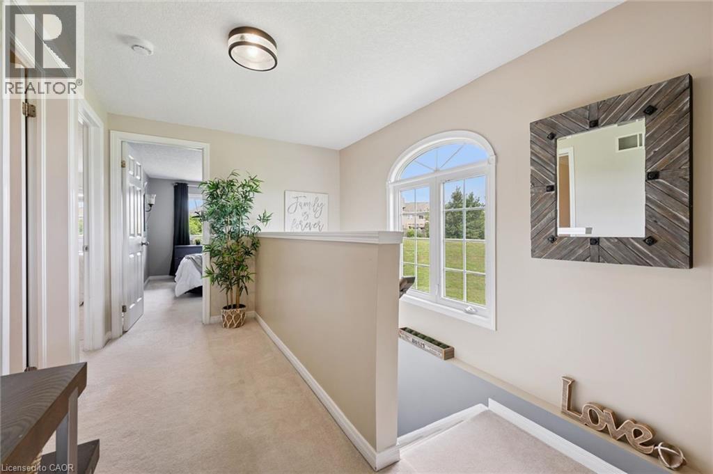 Bright upper hallway featuring light-colored carpeting, a stylish arched window, and a modern flush-mount light fixture - 308 Parkvale Drive, Kitchener, ON - Indoor Photo Showing Other Room
