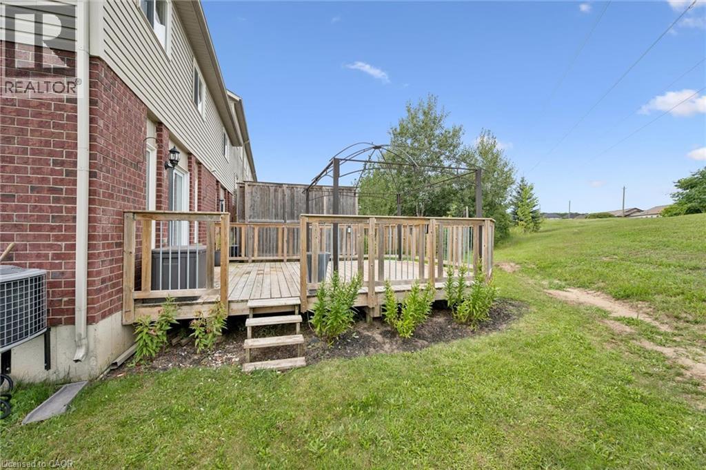 Wood deck with railing and steps, exterior brick and siding, and expansive grassy area - 308 Parkvale Drive, Kitchener, ON - Outdoor