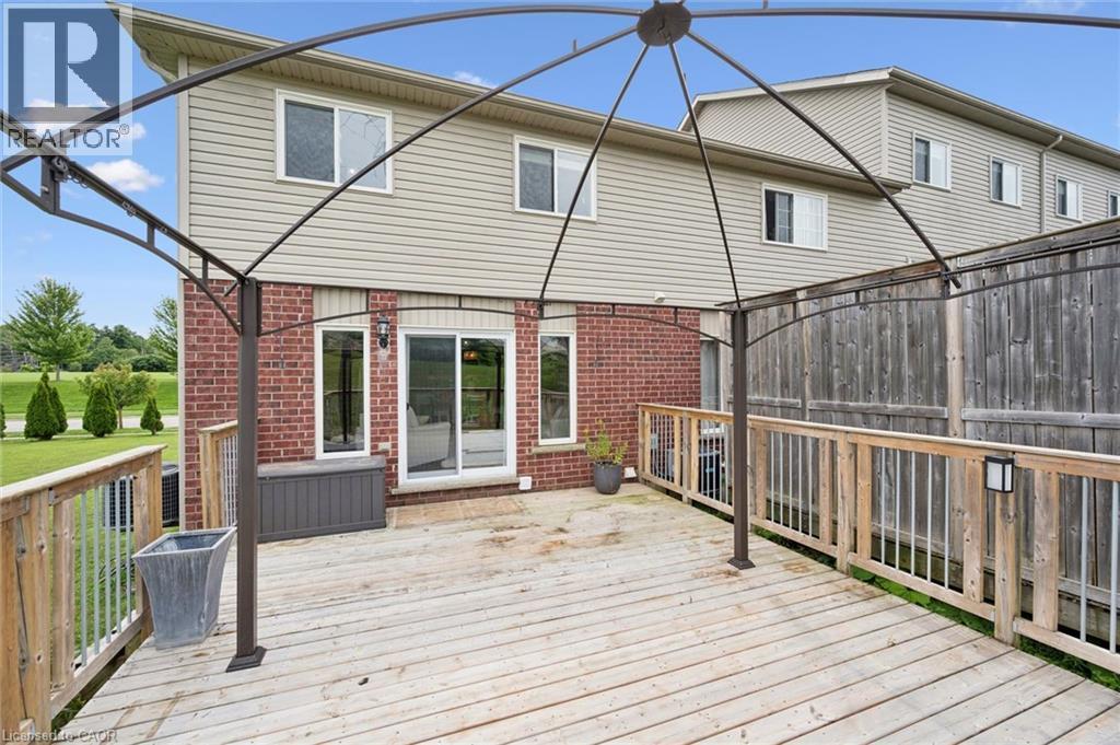 Ground-level wood deck with a metal gazebo frame, brick exterior wall, and sliding glass doors - 308 Parkvale Drive, Kitchener, ON - Outdoor With Deck Patio Veranda With Exterior