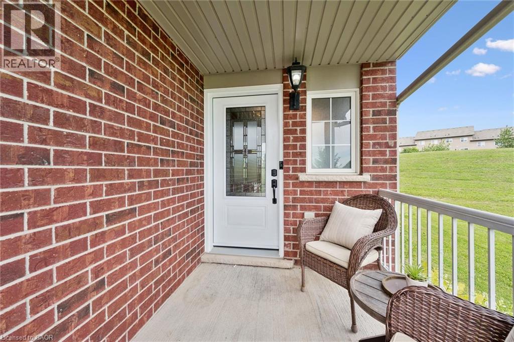 Brick exterior wall, covered concrete porch, white entry door with decorative glass, white-framed window, and exterior wall lantern - 308 Parkvale Drive, Kitchener, ON - Outdoor With Exterior