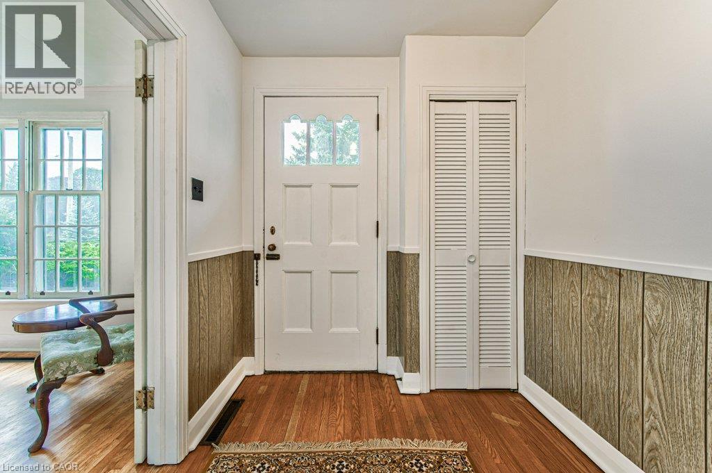 Hardwood flooring, paneled walls, white paneled door with decorative glass inserts, and louvered bifold closet doors - 321 Highland Park, Cambridge, ON