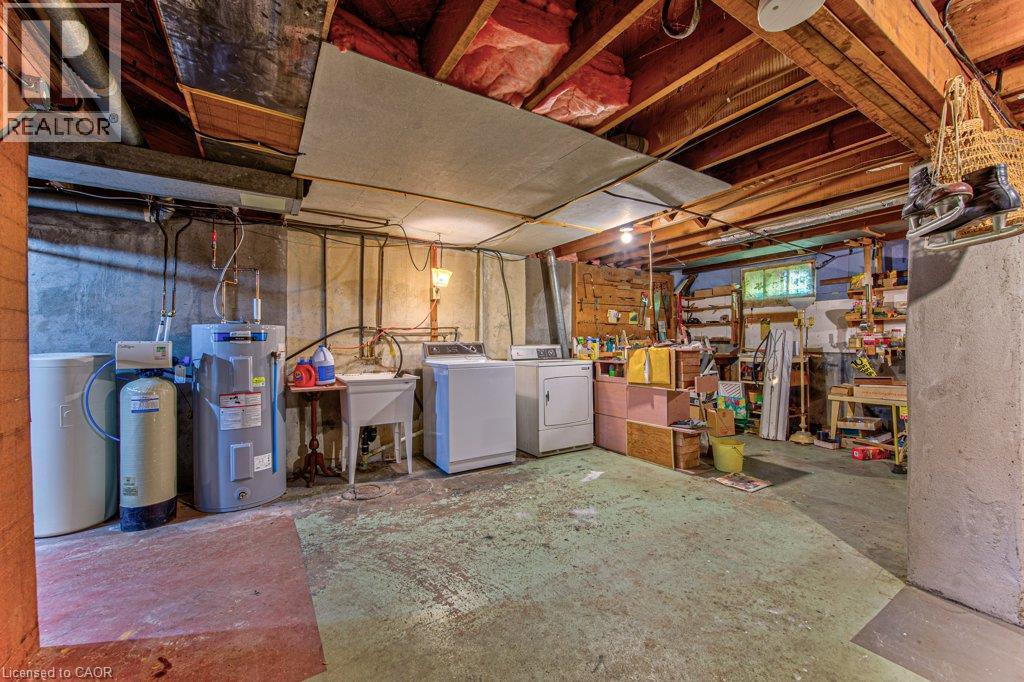 Basement utility area featuring exposed wood beam ceiling, concrete flooring, washer, dryer, and a utility sink - 321 Highland Park, Cambridge, ON