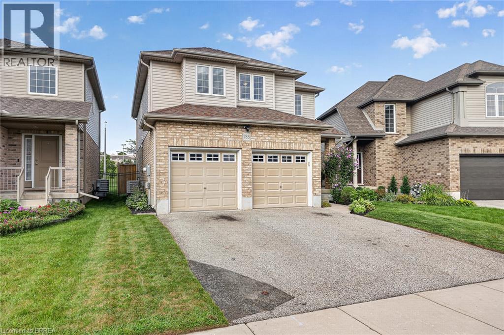 Two-story residence featuring a brick and siding exterior, a two-car garage, an asphalt driveway, and a landscaped front yard - 783 Frontenac Crescent, Woodstock, ON - Outdoor