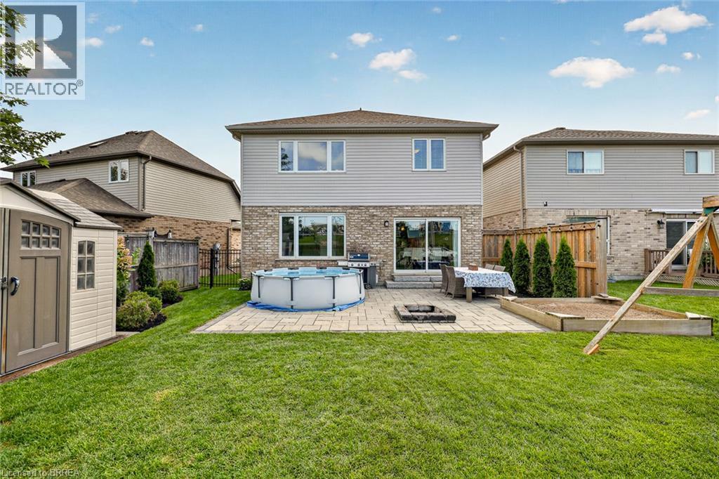 Expansive rear yard featuring a manicured lawn, paver patio, integrated fire pit, and a storage shed - 783 Frontenac Crescent, Woodstock, ON - Outdoor With Above Ground Pool With Exterior