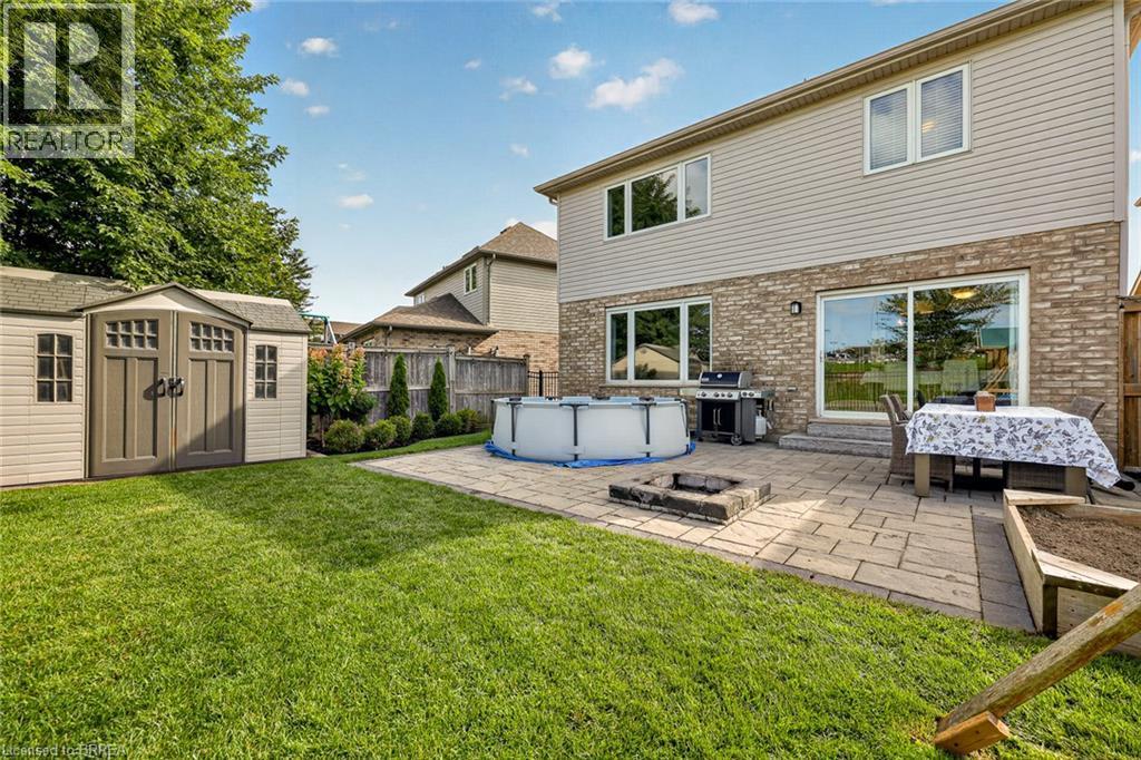 Expansive backyard featuring a manicured lawn, a large paver patio, a built-in stone fire pit, and a storage shed - 783 Frontenac Crescent, Woodstock, ON - Outdoor With Above Ground Pool With Exterior