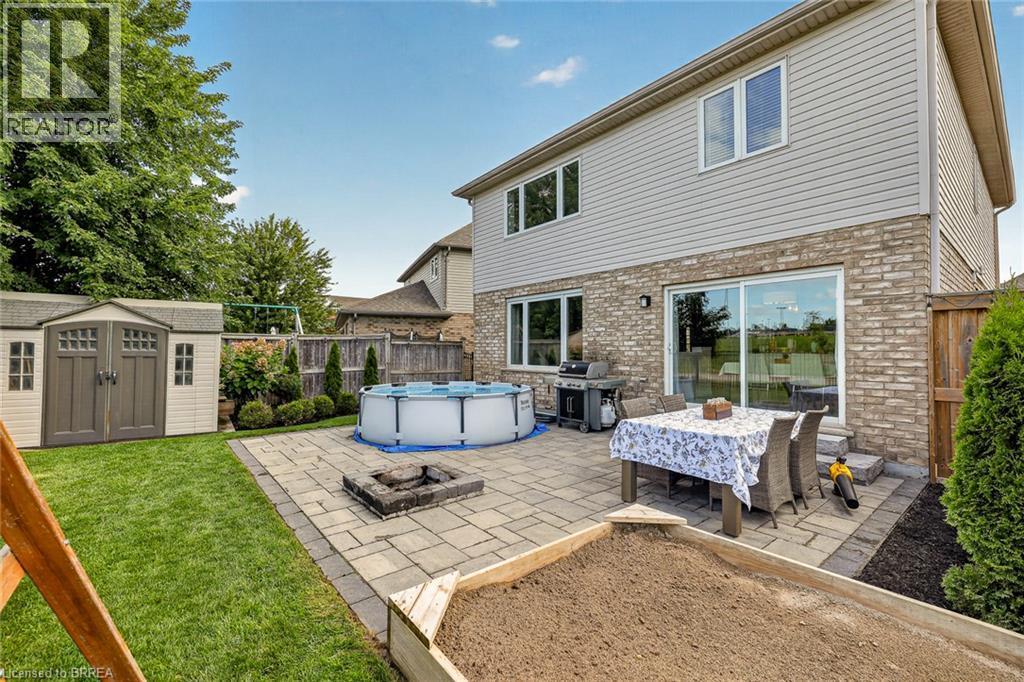 Expansive backyard featuring a paver patio, built-in fire pit, and a storage shed - 783 Frontenac Crescent, Woodstock, ON - Outdoor With Above Ground Pool With Exterior