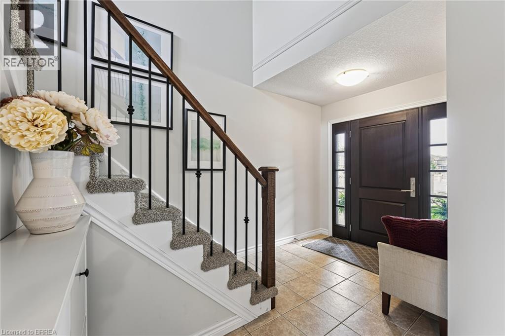 Warm tiled flooring with a dark wood-finish entry door featuring sidelight windows - 783 Frontenac Crescent, Woodstock, ON - Indoor Photo Showing Other Room
