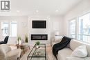 Living area featuring an integrated electric fireplace, recessed lighting, and large windows - 297 Britannia Avenue, Hamilton, ON  - Indoor Photo Showing Living Room With Fireplace 