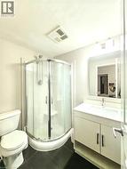 Corner shower enclosure with sliding glass doors, white vanity with integrated sink, wall-mounted mirror, and dark tile flooring - 