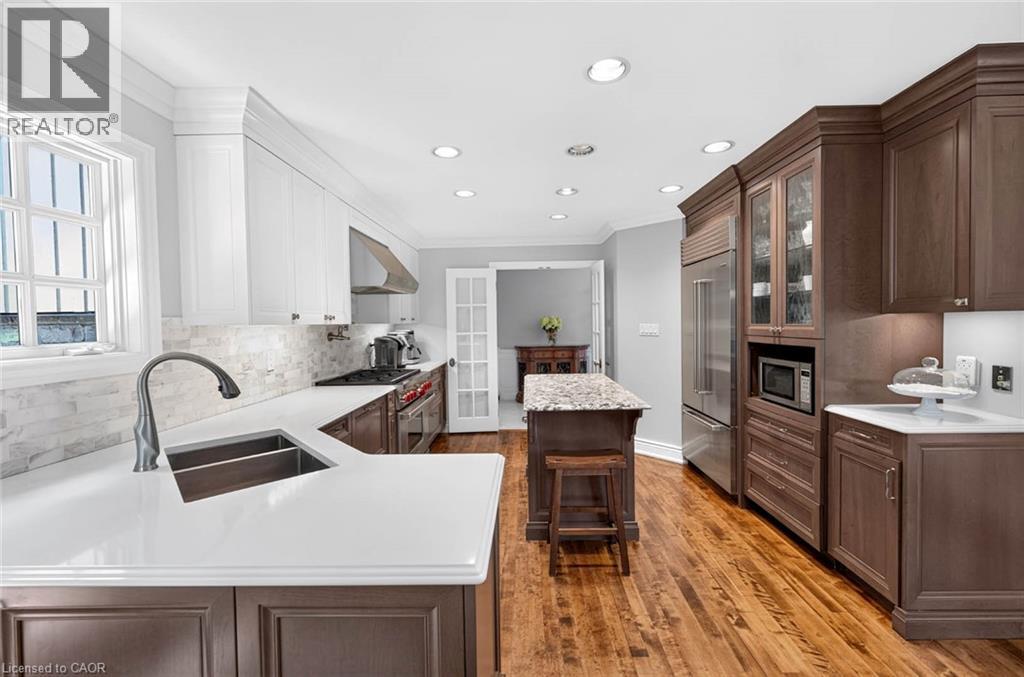 Gourmet kitchen with wood-finish flooring, recessed lighting, white and wood-finish cabinetry, stainless steel appliances, and a central island with a stone-finish countertop - 11 Christman Court, Markham, ON - Indoor Photo Showing Kitchen With Double Sink With Upgraded Kitchen